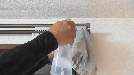 カーテンランナーの清掃時にスプレー洗剤を吹き付けると裏側の壁紙クロスに汚れが飛ぶので、その防止策として裏側に雑巾を当てながらスプレーをします。